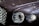 Close-up of a polished luxury car exterior reflecting city lights at dusk.