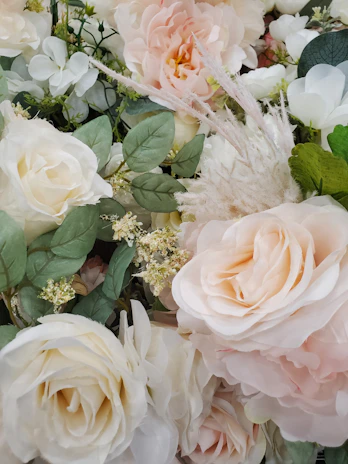 Elegant wedding floral arrangement with soft pastel roses and greenery in a bright venue.
