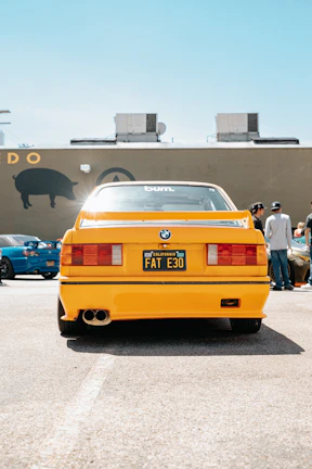 A happy customer proudly showing off their car with a Fat Boy Frame at a used car lot.