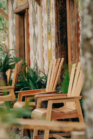 Outdoor seating area with rustic wooden chairs surrounded by lush forest greenery
