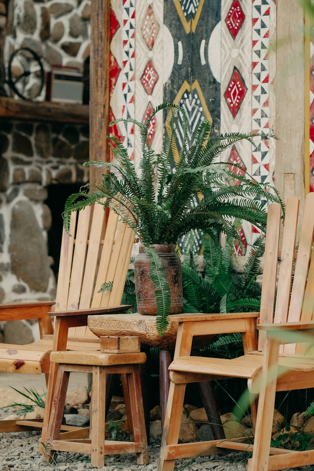 a couple of wooden chairs sitting next to a potted plant