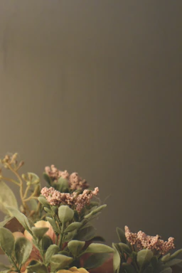Close-up of an elegant, contemporary floral arrangement with deep green and beige tones against a minimalist white background.