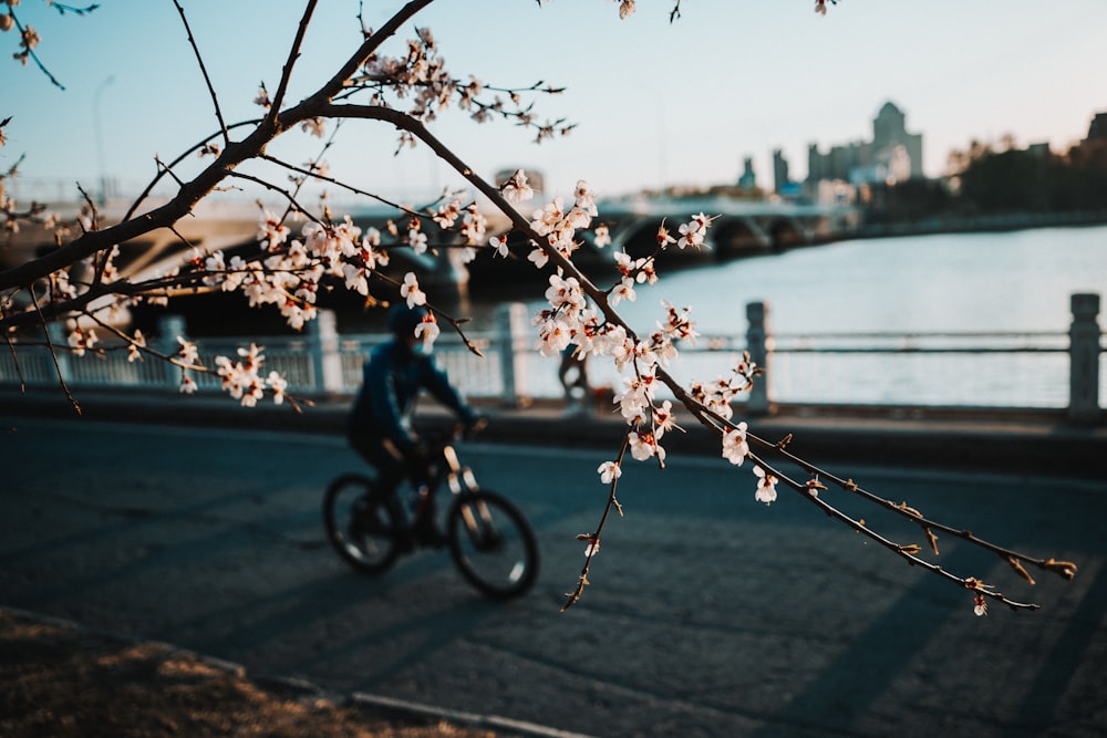 a man riding a bike down a street next to a river