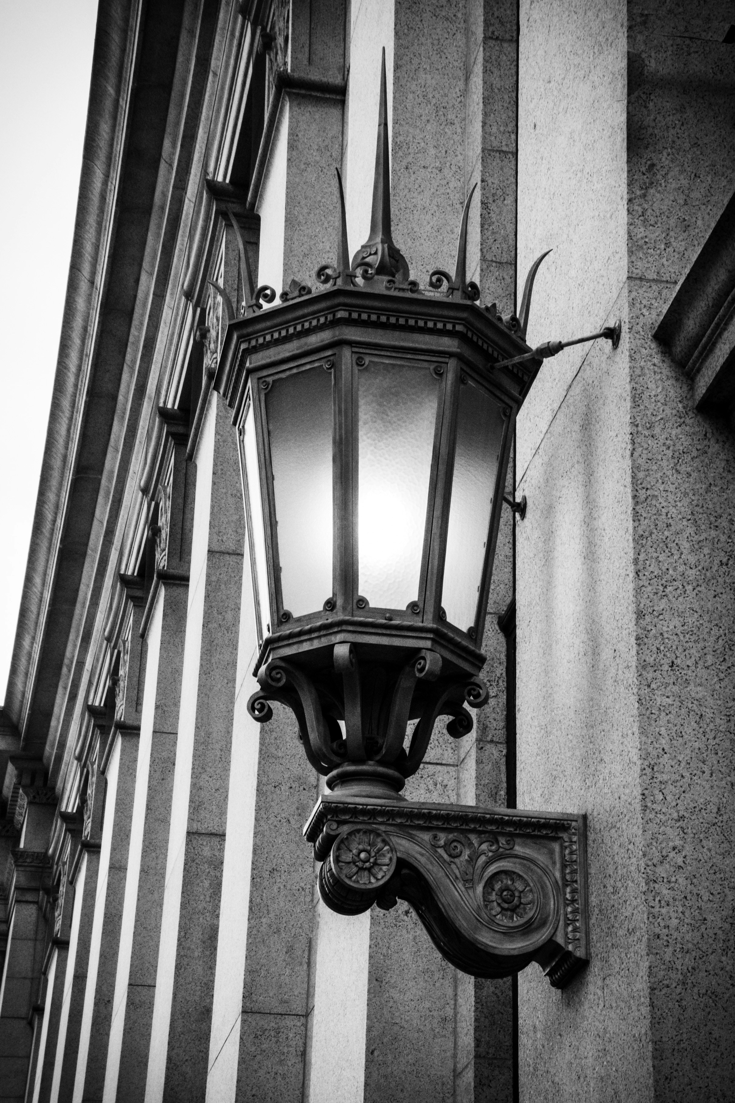 an ornate lantern with scrolled iron base and faceted glass on a prewar building
