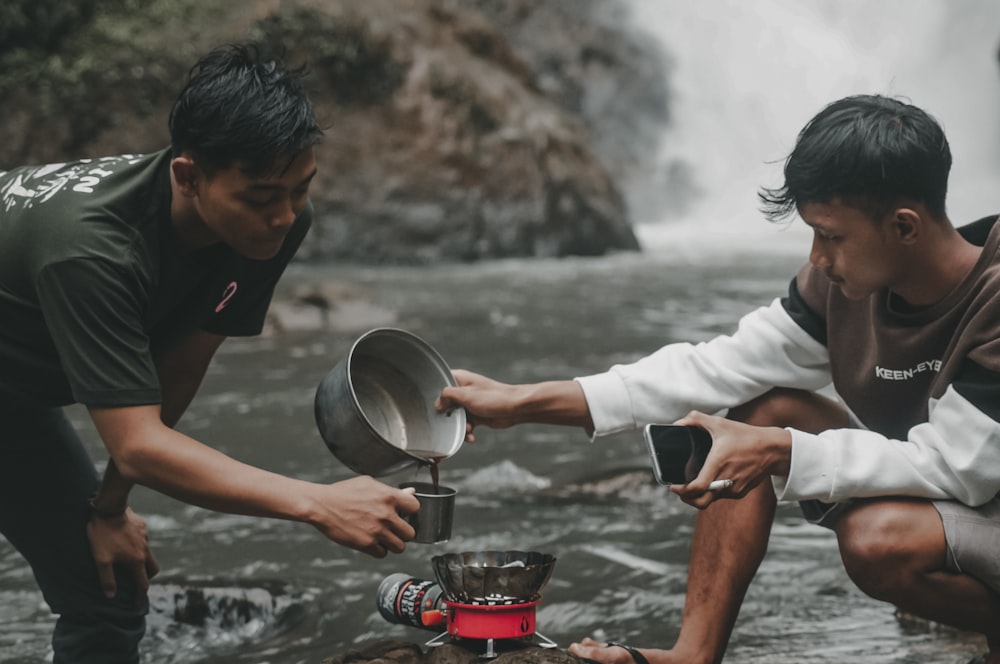 two men are preparing food in a stream