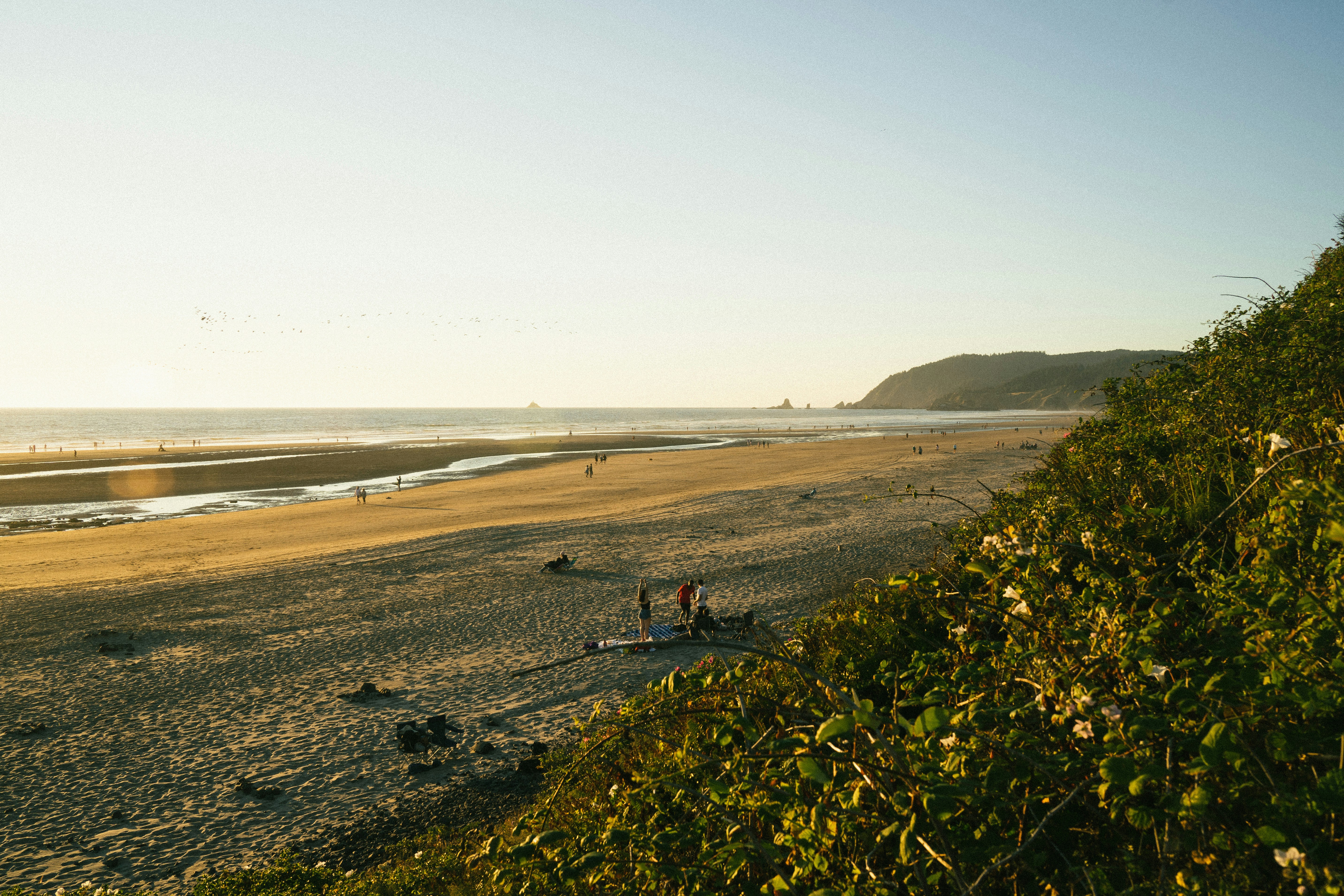 um grupo de pessoas em pé no topo de uma praia de areia