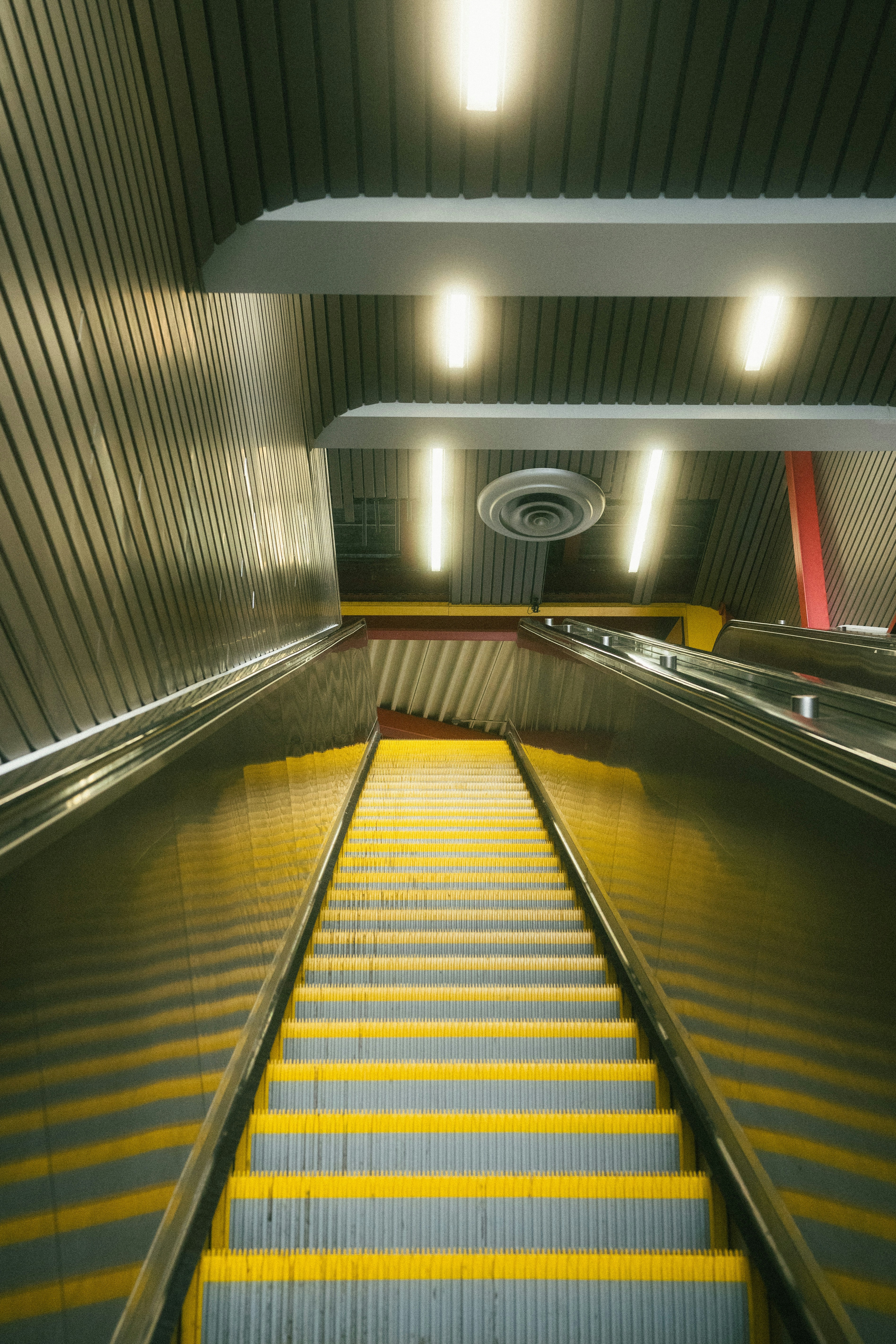 uma escada rolante em uma estação de metrô com degraus amarelos