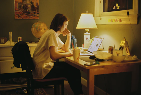 A warm, inviting portrait of a solo entrepreneur working intently at a cozy desk, surrounded by project notes and a laptop.