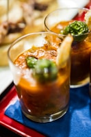 Close-up of a frosty beer mug next to a bowl of spicy caldo de camarón.