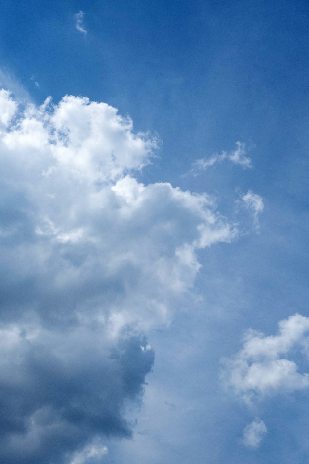 a plane flying through a cloudy blue sky