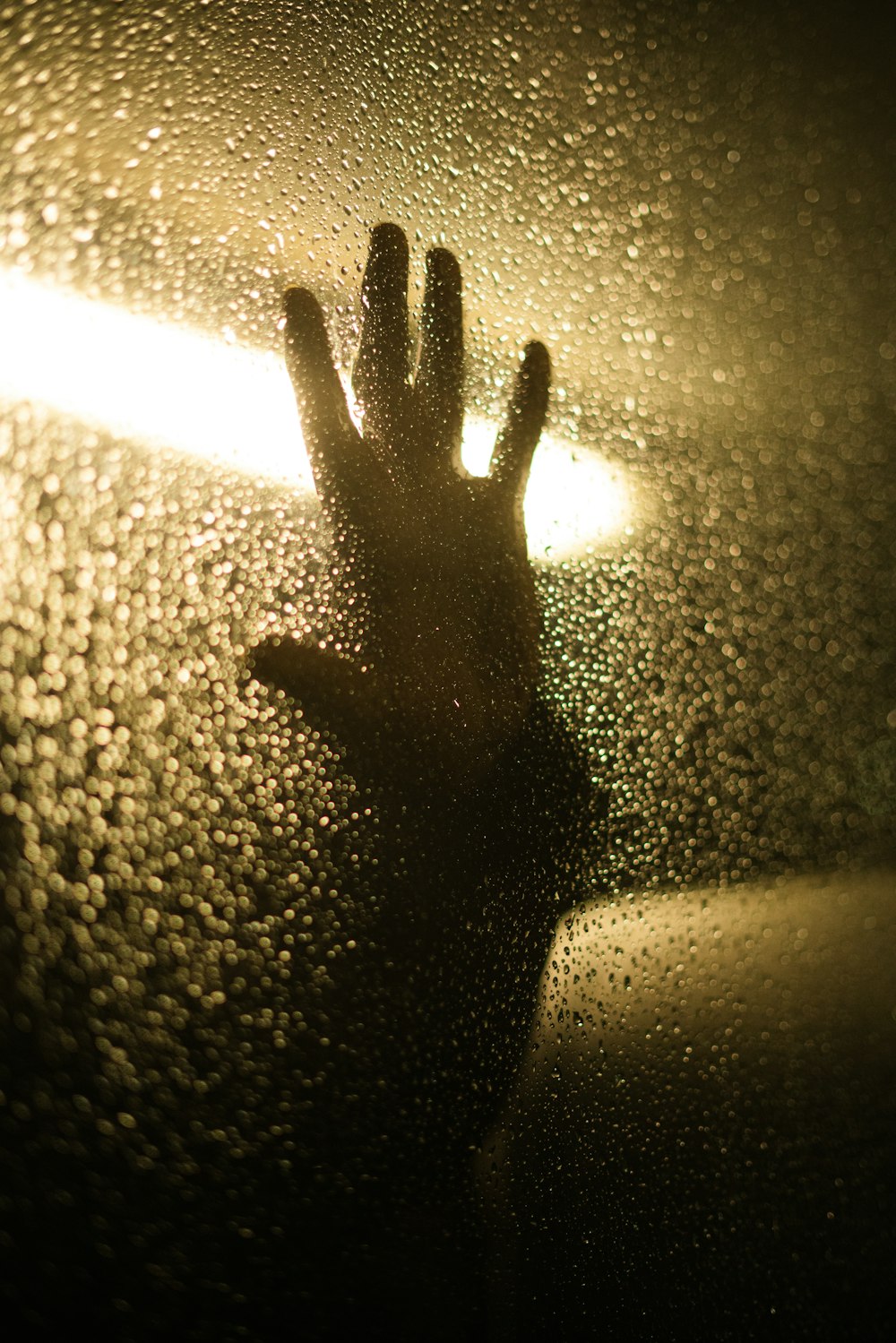 a person's hand on a wet window