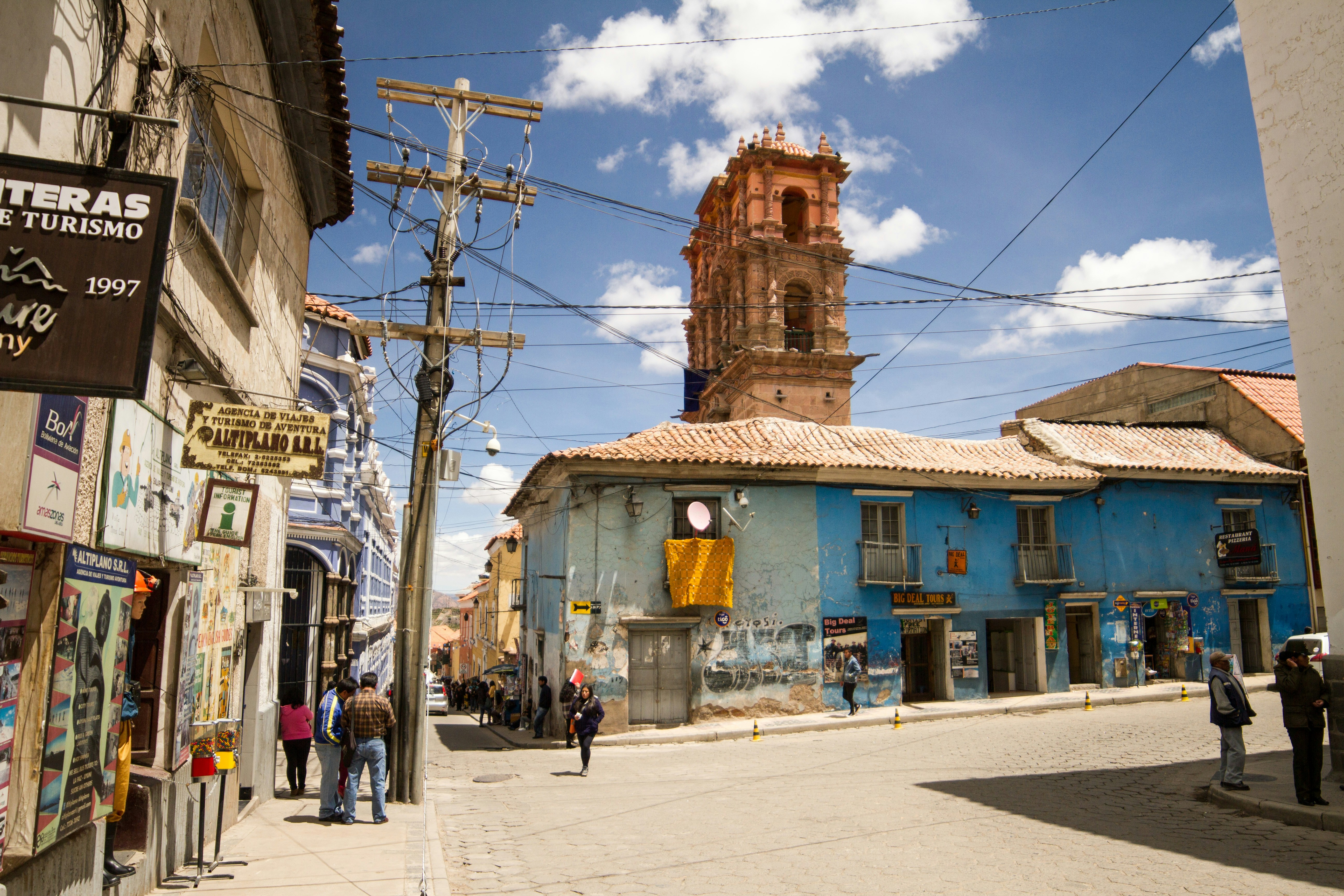 a group of people walking down a street next to tall buildings, 