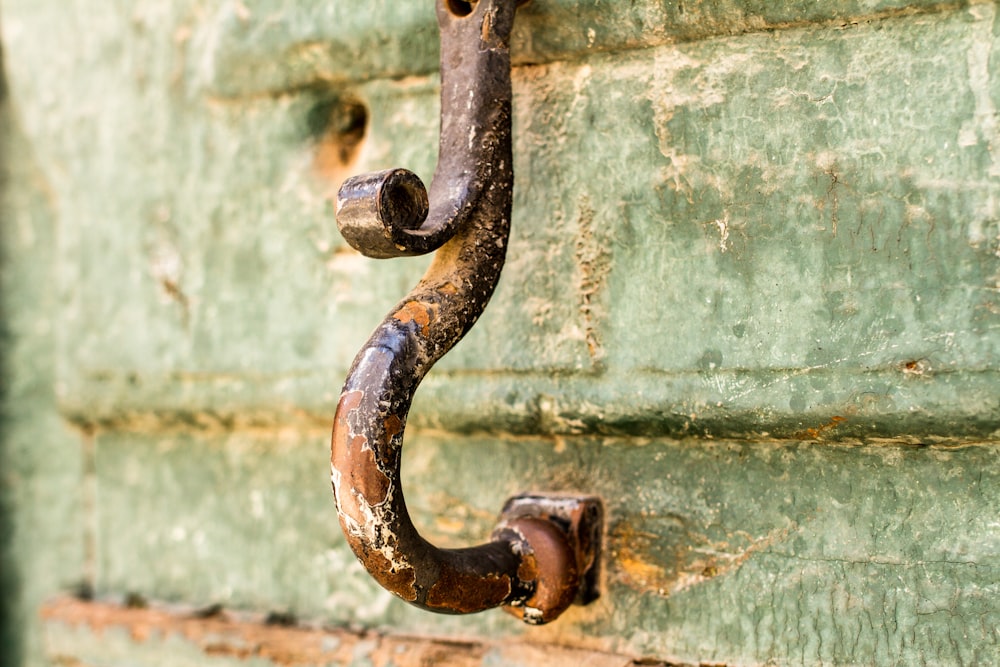 a rusted metal hook on a green wall