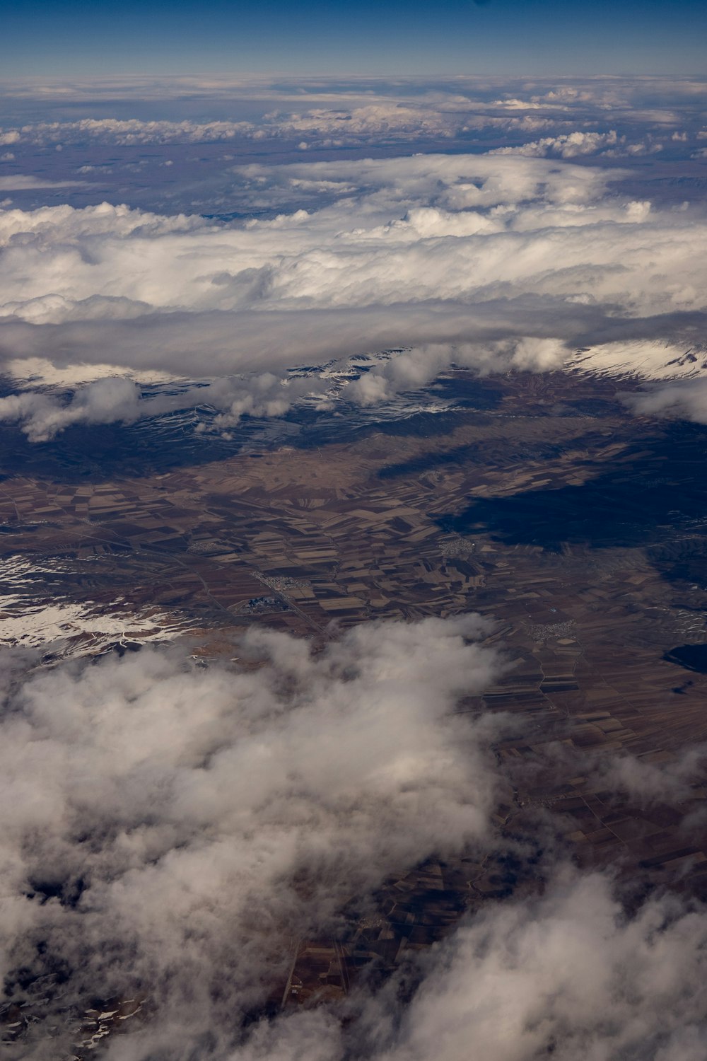 an aerial view of clouds and land from an airplane