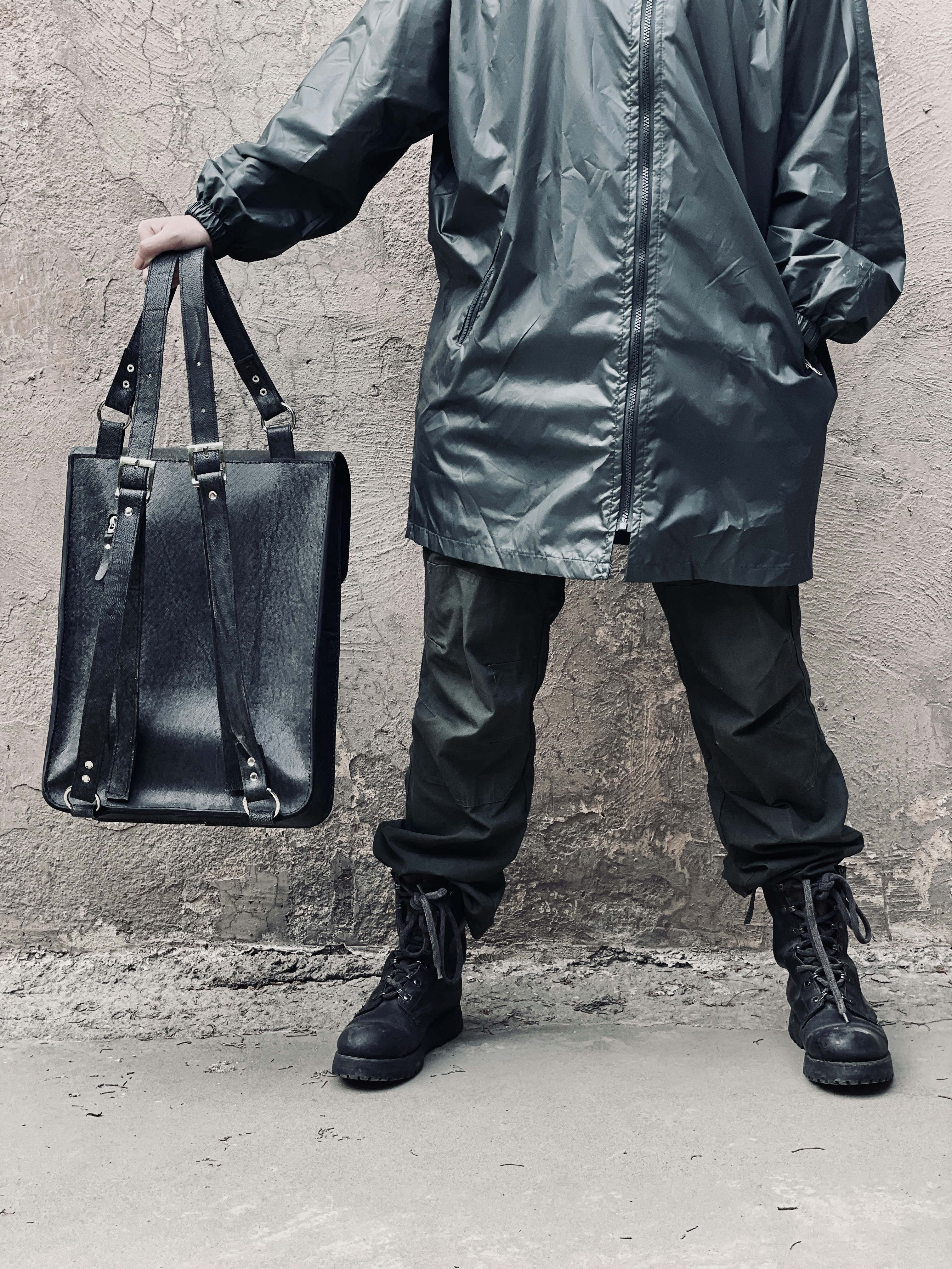 um homem em uma capa de chuva segurando um saco preto