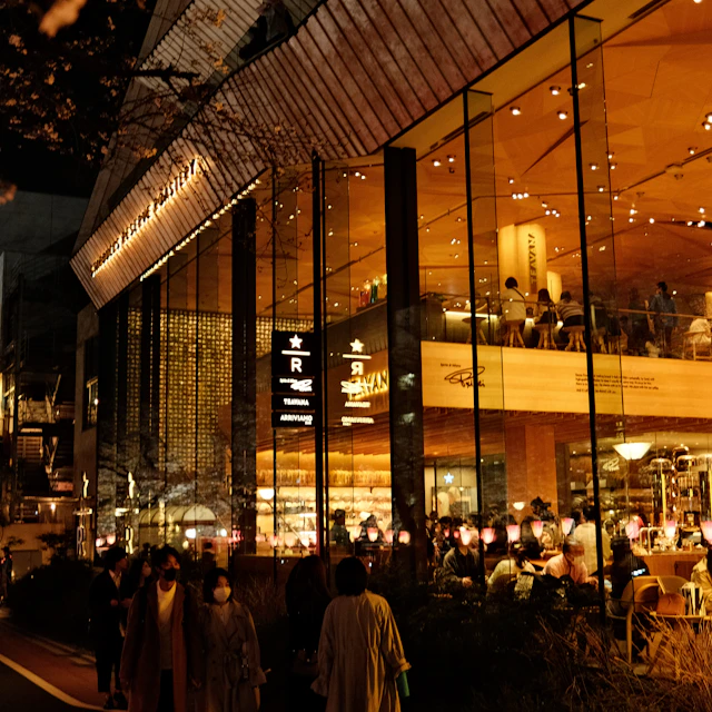 A group of people standing outside a lit building at night in Nakameguro, Tokyo