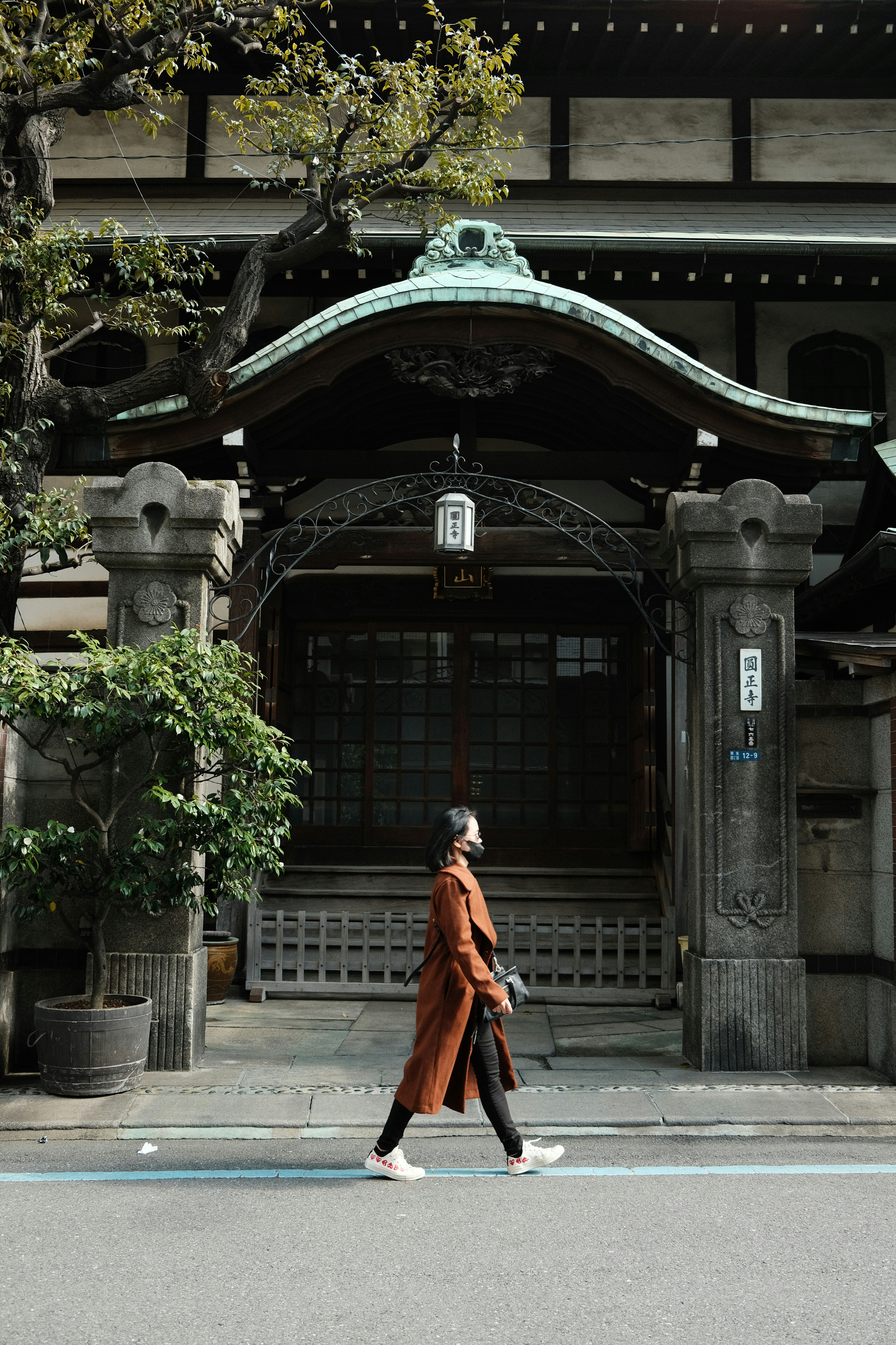 a woman walking across a street in front of a building