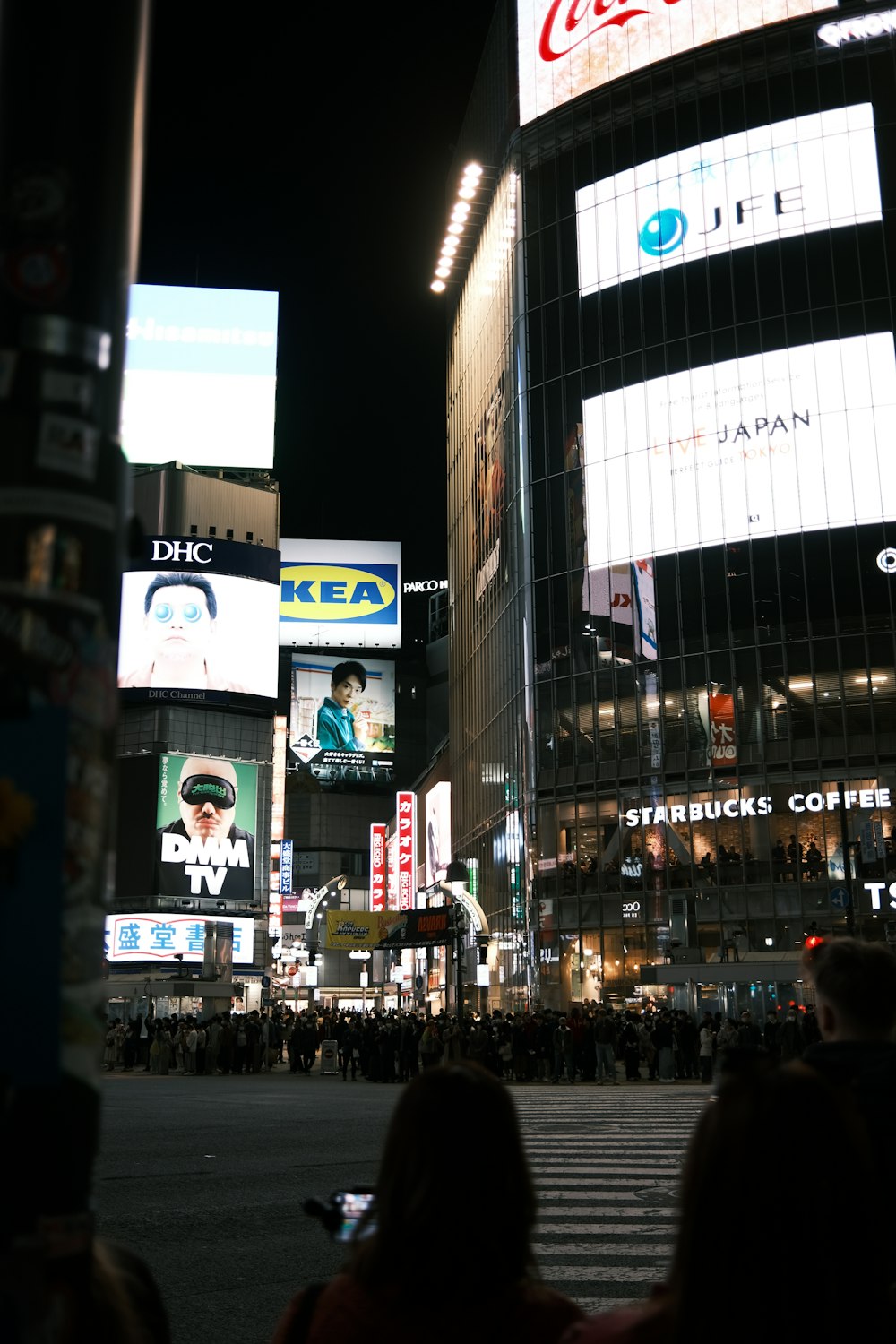 a busy city street at night with people crossing the street