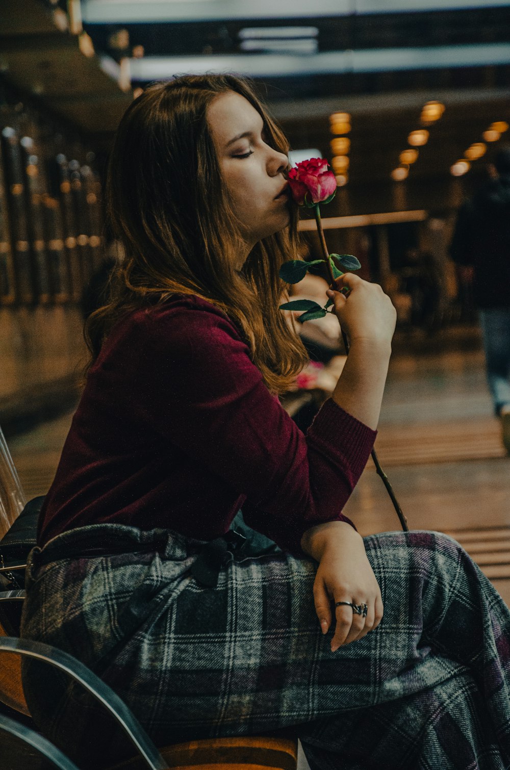 a woman sitting on a bench with a flower in her mouth