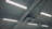 Fluorescent lights are mounted on the ceiling along with an air conditioning unit. The ceiling is structured with beams, and several cables and wires are connected to the lights and the unit.