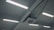 Fluorescent lights are mounted on the ceiling along with an air conditioning unit. The ceiling is structured with beams, and several cables and wires are connected to the lights and the unit.