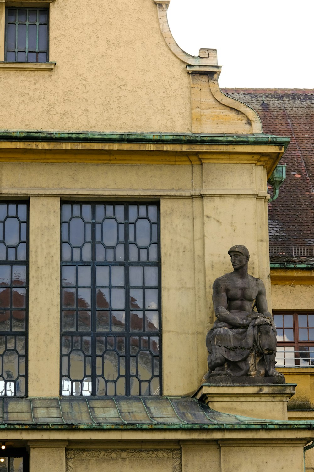 a statue of a man sitting on a bench in front of a building