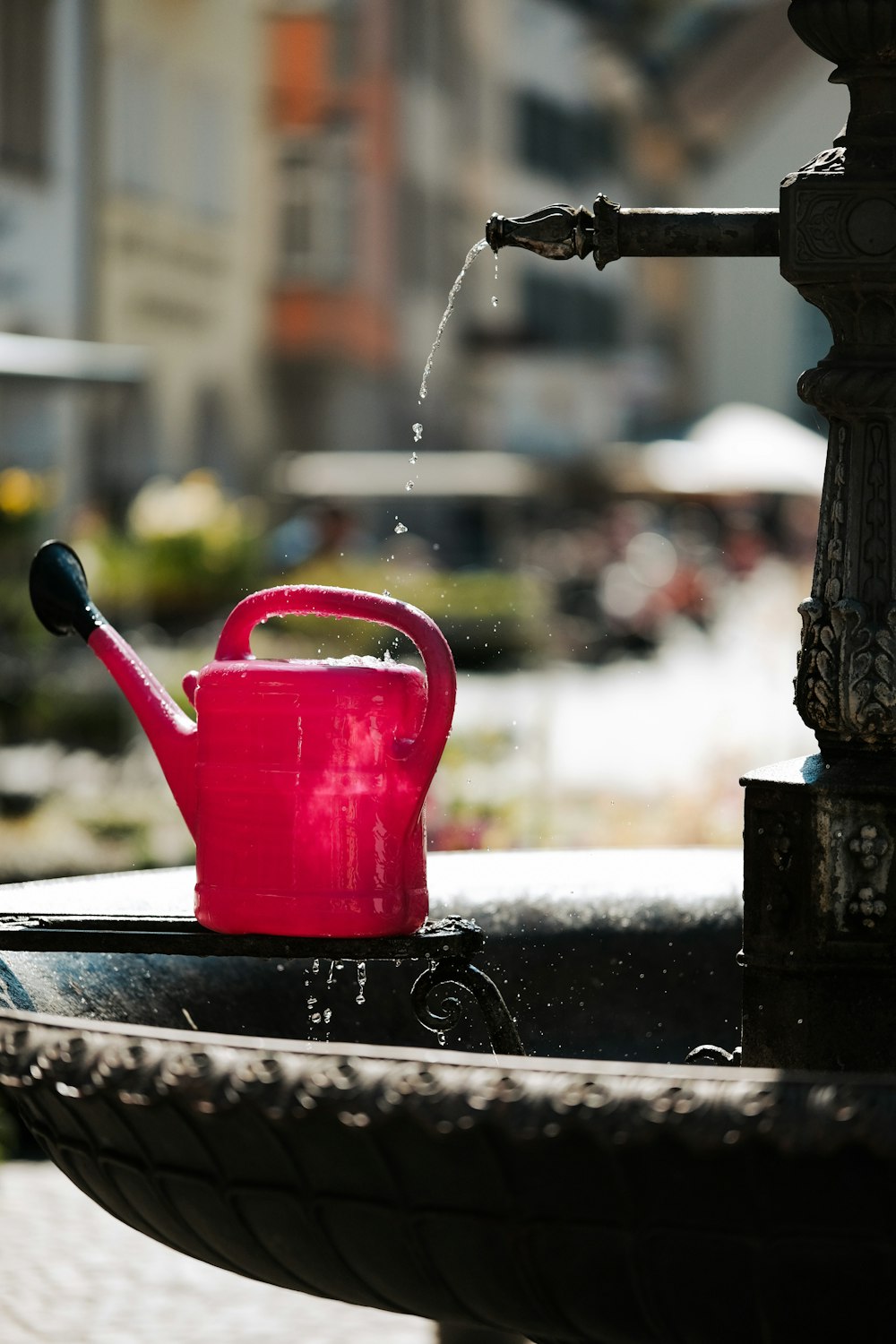 un arrosoir rose posé au sommet d’une fontaine