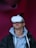 A person wearing a virtual reality headset appears to be engaged or immersed in the experience. They are dressed in a casual outfit consisting of a hoodie and a jacket, with a light-colored background offering a contrast to the darker tones of the clothing.
