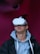 A person wearing a virtual reality headset appears to be engaged or immersed in the experience. They are dressed in a casual outfit consisting of a hoodie and a jacket, with a light-colored background offering a contrast to the darker tones of the clothing.