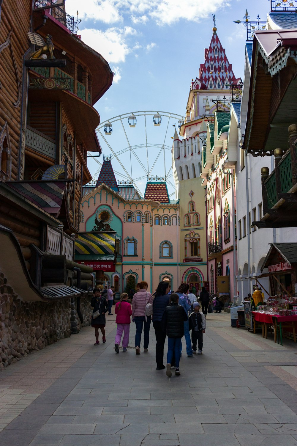 a group of people walking down a street next to a ferris wheel