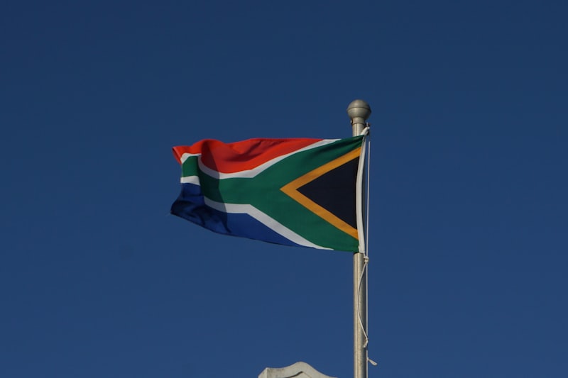 South African flag flying on a flagpole against a clear blue sky