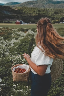 a woman holding a basket of strawberries in a field