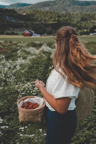 a woman holding a basket of strawberries in a field