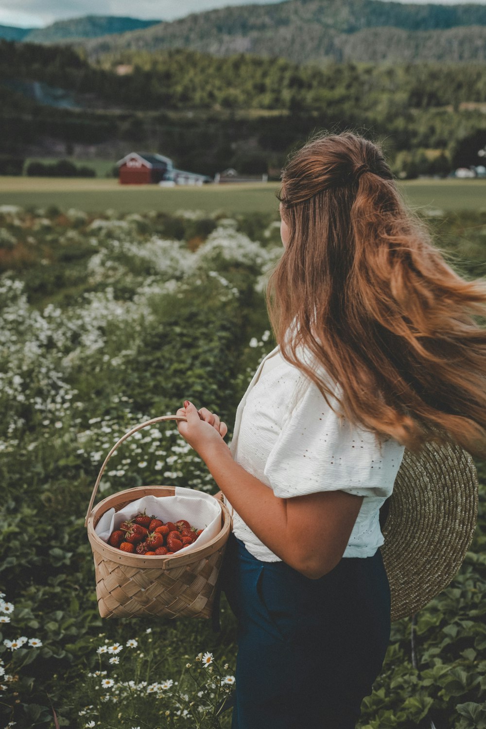 a woman holding a basket of strawberries in a field