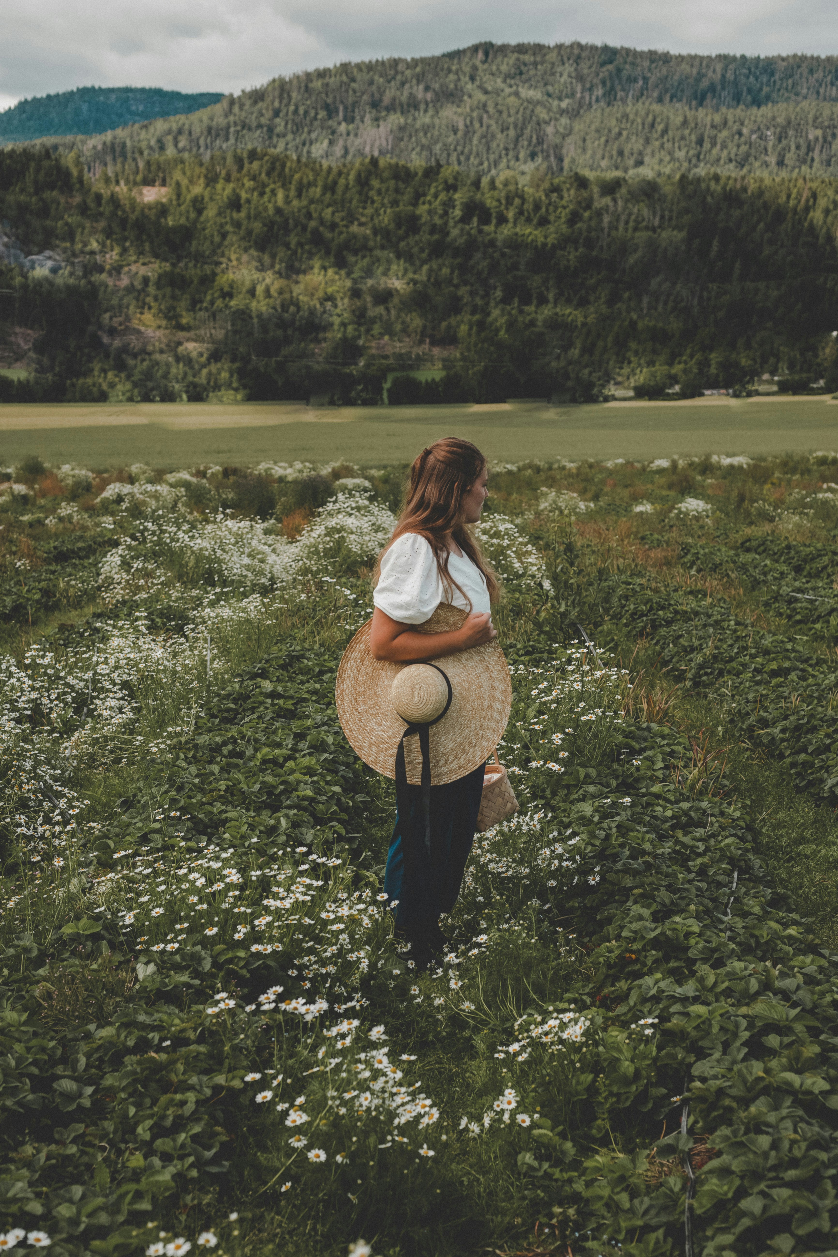 a woman standing in a field with a hat