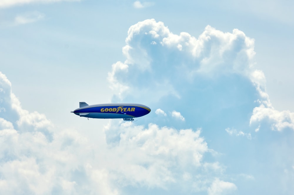 a blue and white jet flying through a cloudy blue sky