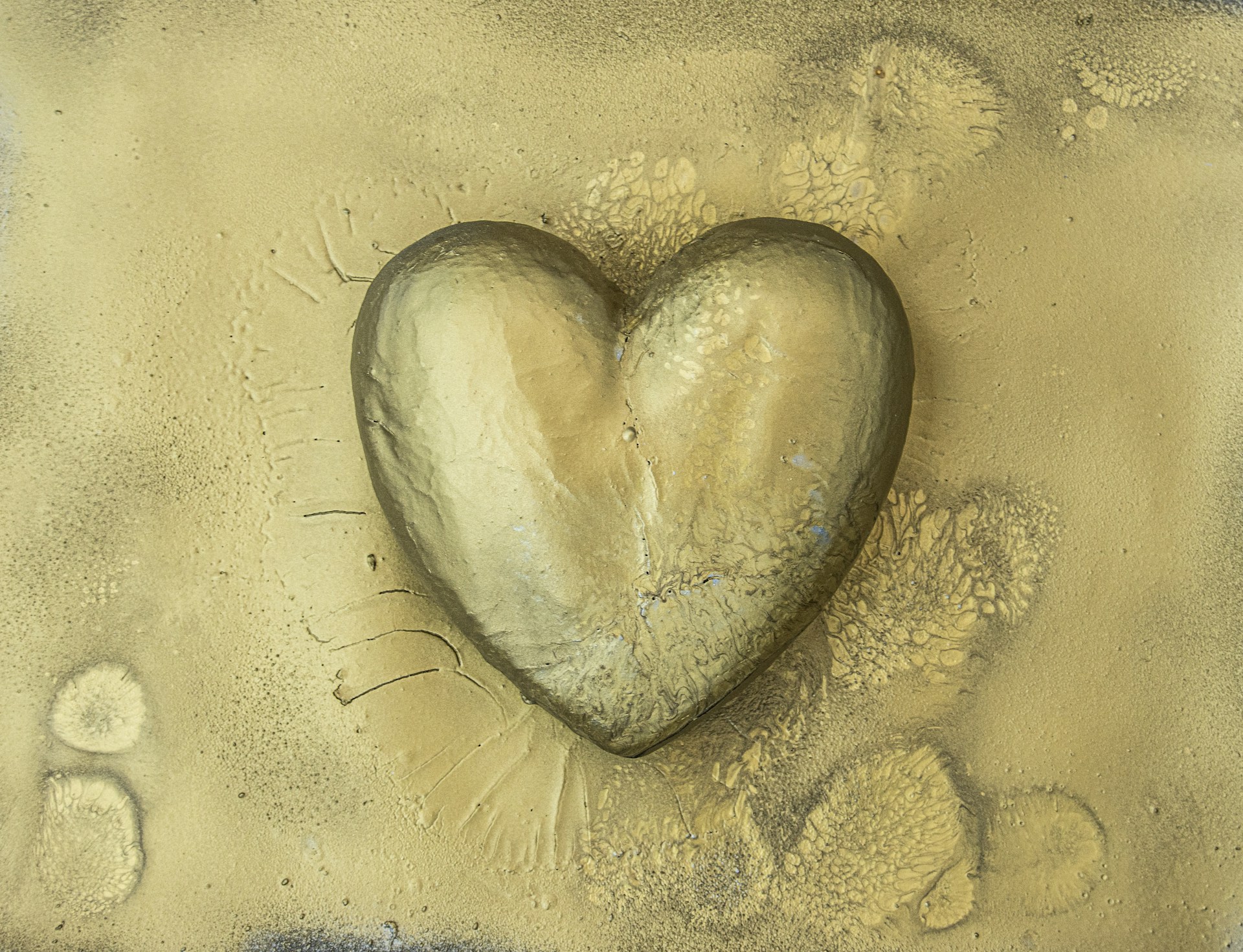 a heart shaped rock sitting on top of a sandy beach