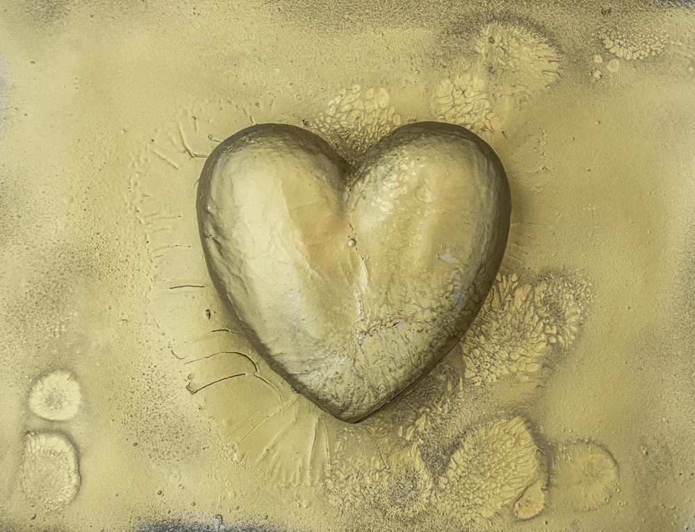a heart shaped rock sitting on top of a sandy beach