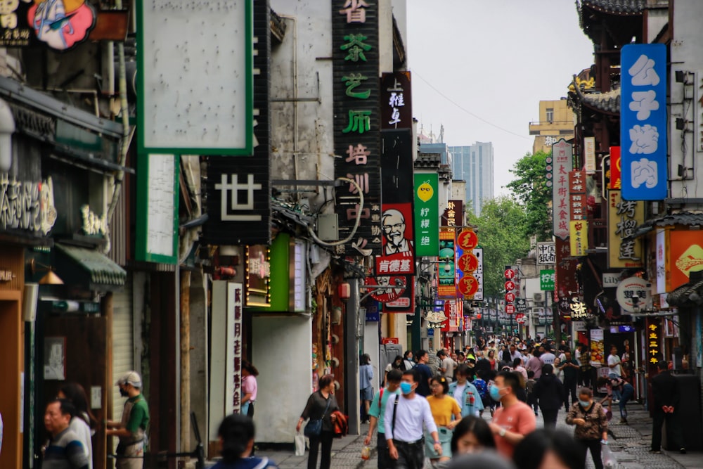 a group of people walking down a street next to tall buildings