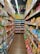 A colorful aisle in a store is lined with various packaged snacks on both sides. Brightly colored bags and boxes create a vibrant and appealing display. Overhead, pink flowers and green leaves hang decoratively from the ceiling. The shelves are stocked with different snack brands, featuring a wide range of colors and designs.