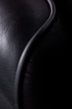 Close-up of smooth charcoal leather texture on a classic noirva jacket sleeve.