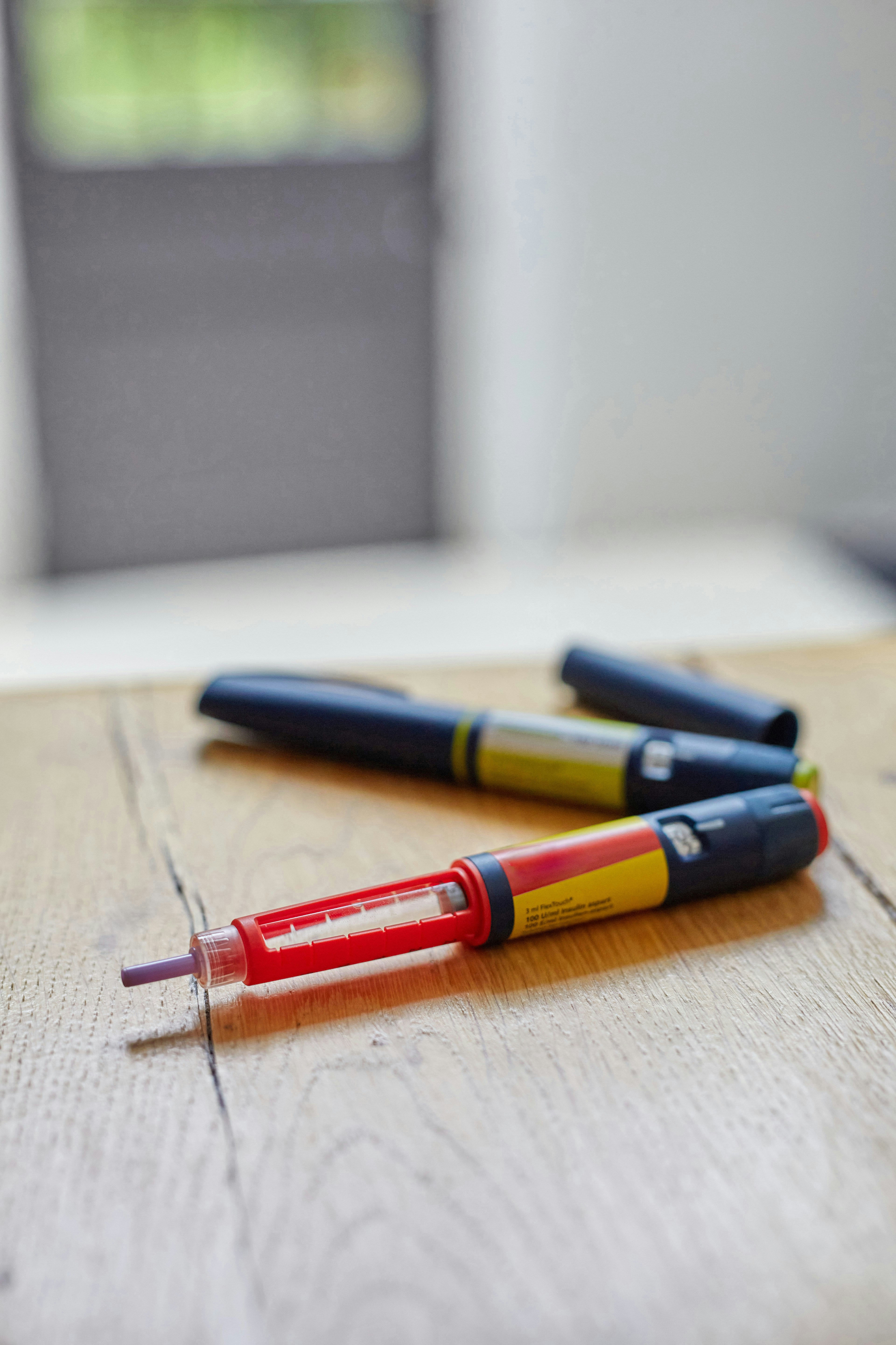 a couple of insulin pens sitting on top of a wooden table