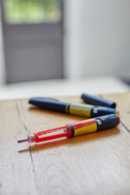 a couple of insulin pens sitting on top of a wooden table