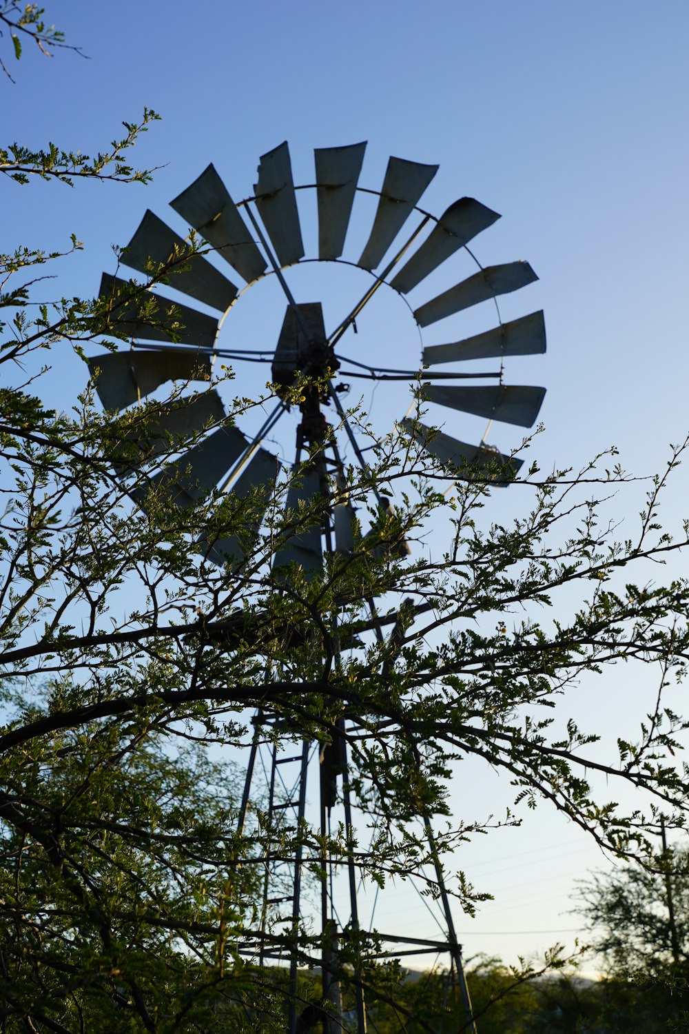 a windmill sitting next to a tree in a field