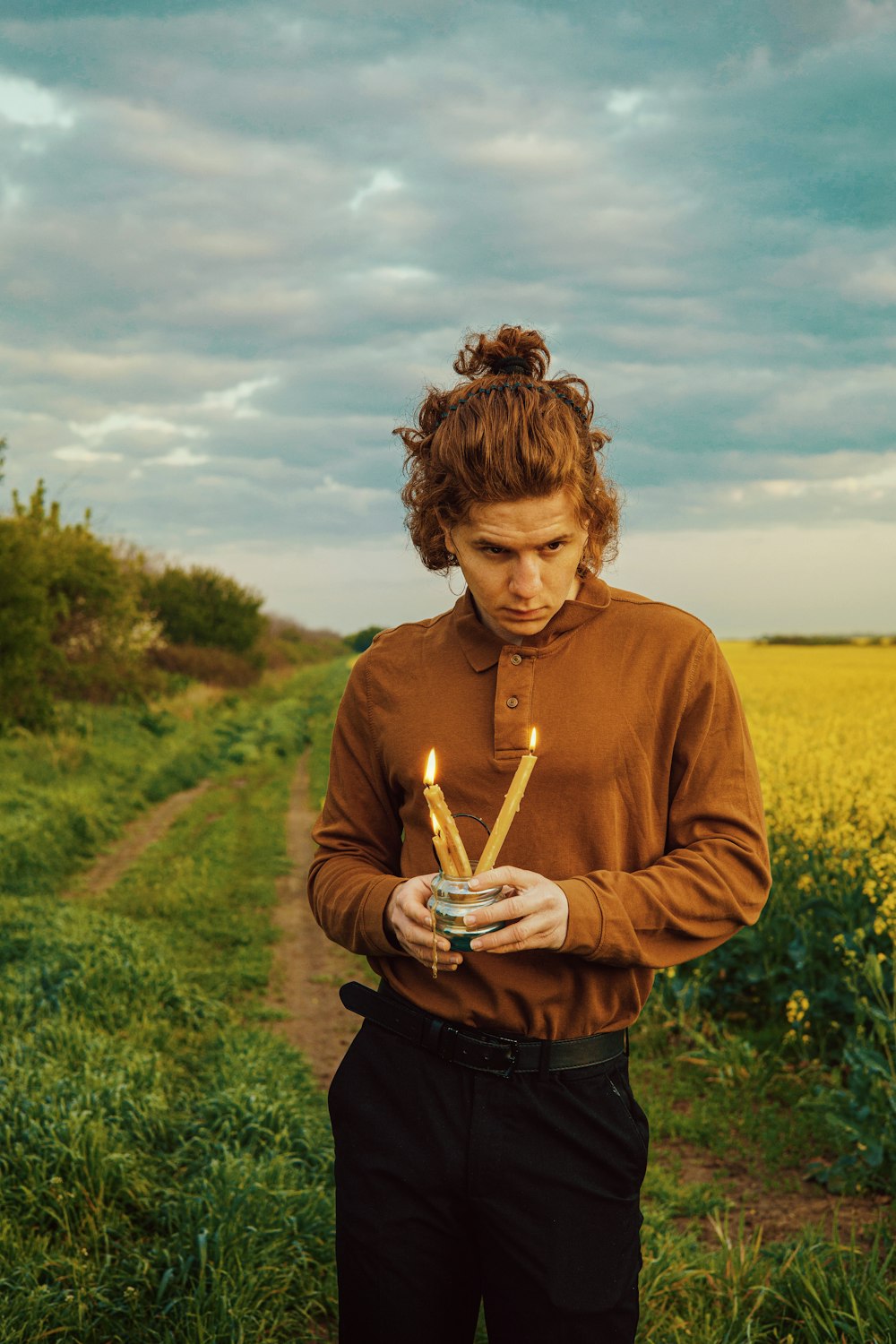 a woman standing in a field holding a candle