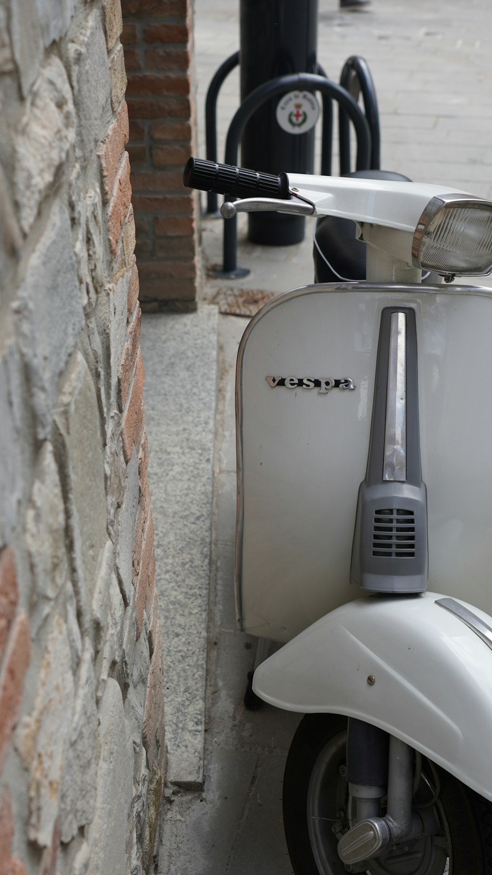 a white scooter parked next to a brick wall