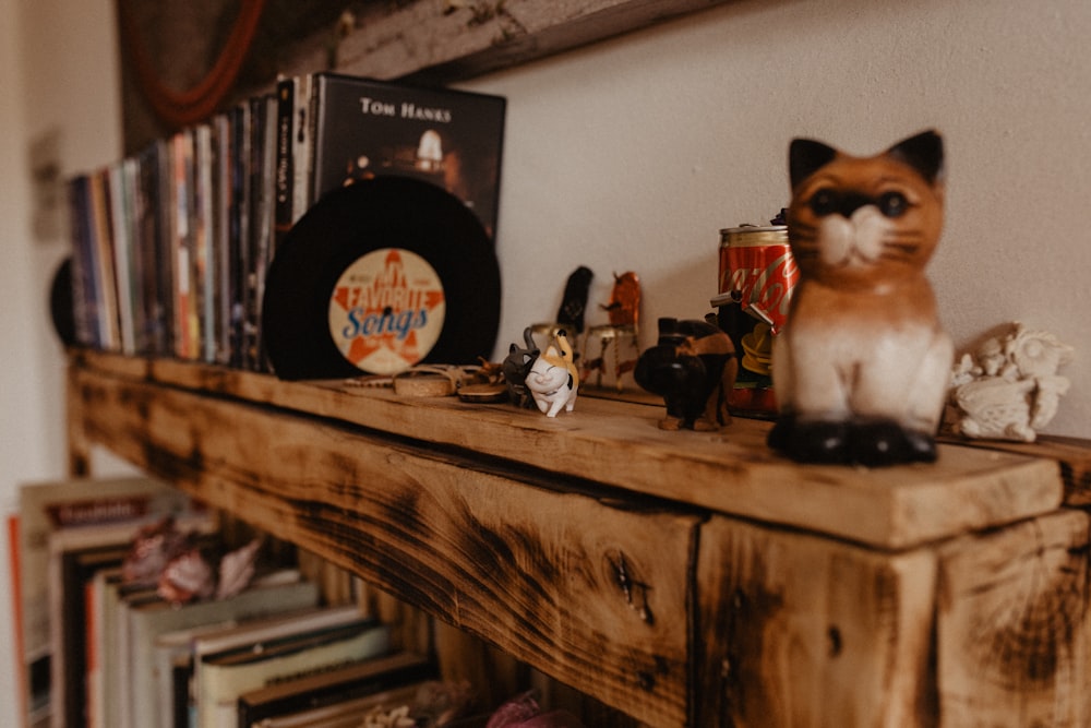 a cat figurine sitting on top of a wooden shelf