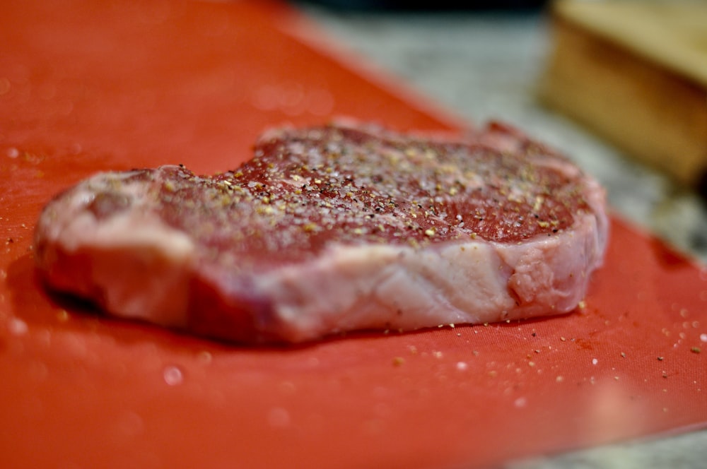 un morceau de viande posé sur une planche à découper rouge