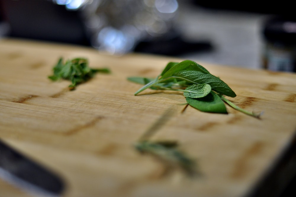 a cutting board topped with green leaves on top of a table