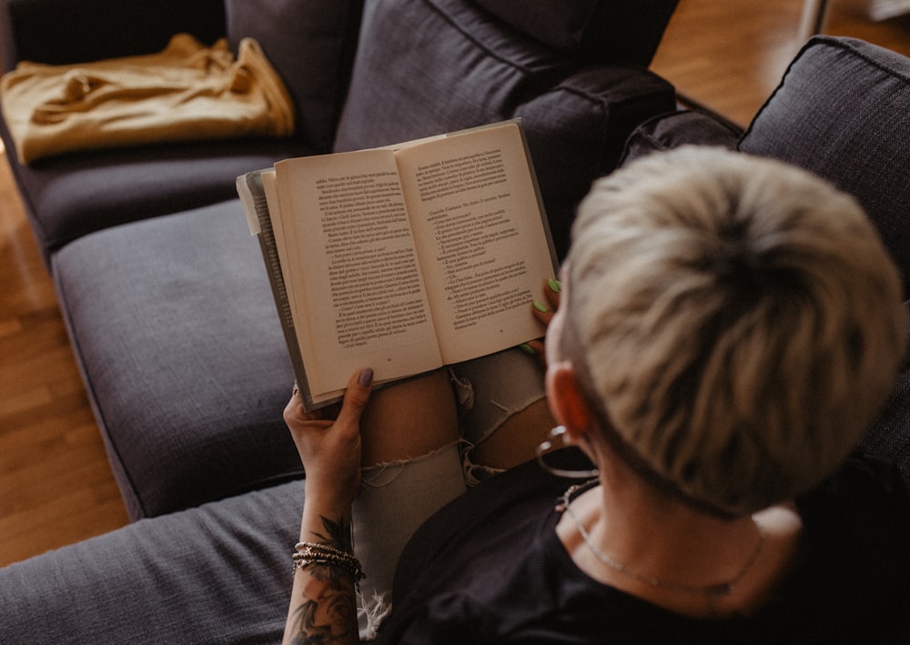 a woman sitting on a couch reading a book